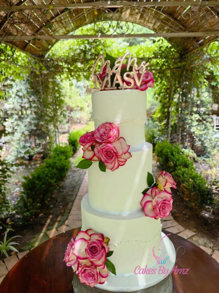 Three-tier ivory wedding cake with pink roses and Mr & Mrs Masv topper