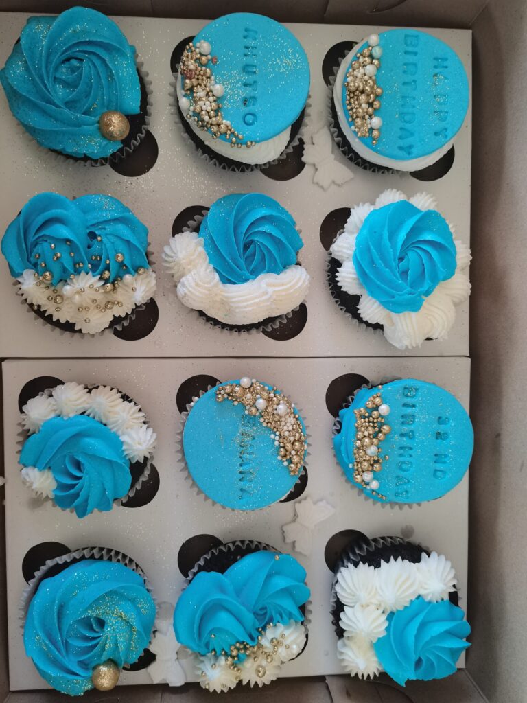 Box of blue and white birthday cupcakes with gold pearls